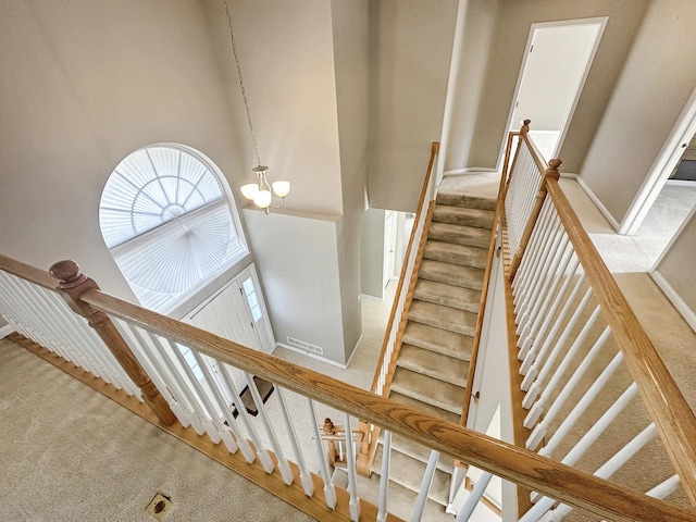 stairs with baseboards, a high ceiling, a chandelier, and carpet