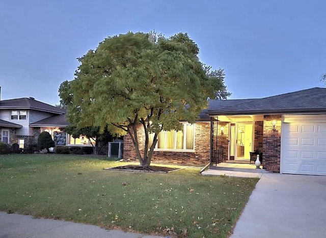 view of front of home with driveway, brick siding, a garage, and a front lawn