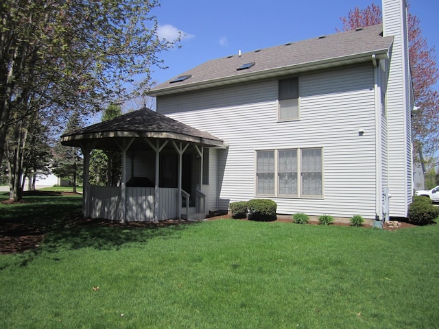 106 Tygert Ln, Dekalb, IL 60115 - back of property featuring a lawn, roof with shingles, a gazebo, and a chimney