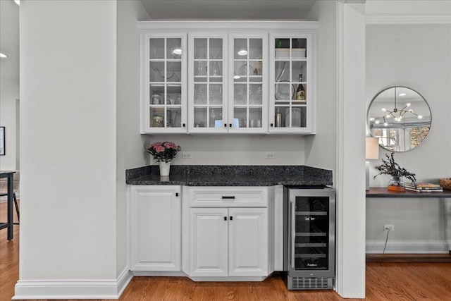 bar with baseboards, wine cooler, and wood finished floors