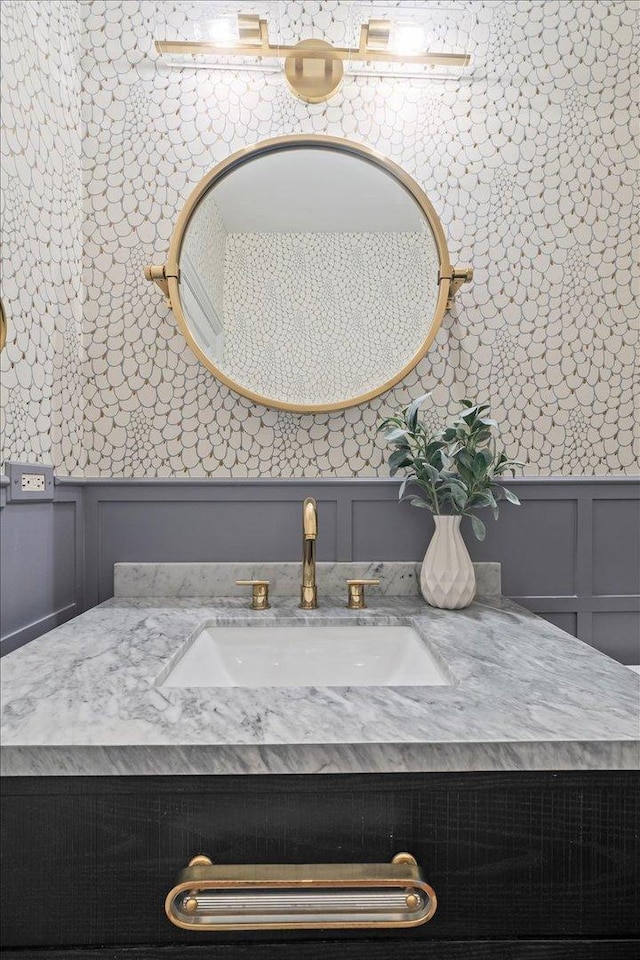 bathroom featuring a decorative wall, vanity, and a wainscoted wall