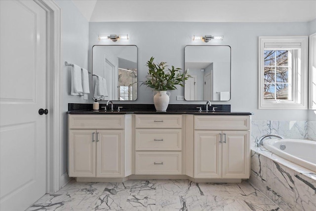 full bathroom with double vanity, marble finish floor, a garden tub, and a sink