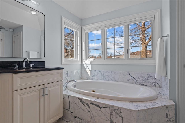 full bathroom featuring vanity, a jetted tub, and a healthy amount of sunlight