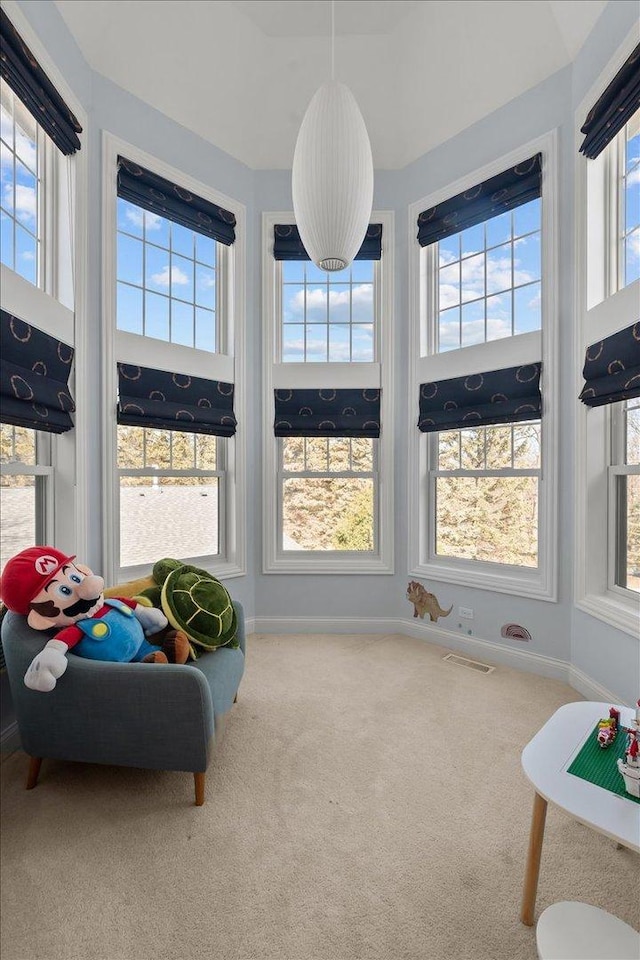 living area with carpet flooring, baseboards, visible vents, and a towering ceiling
