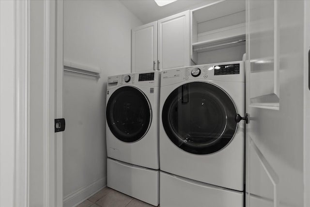 laundry area featuring light tile patterned floors, baseboards, cabinet space, and washing machine and dryer
