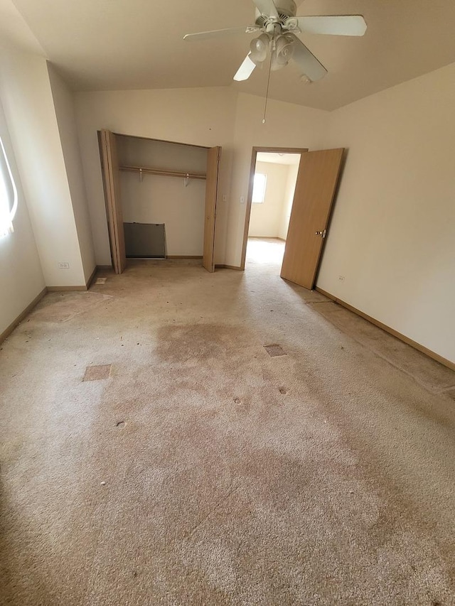 unfurnished bedroom featuring a closet, baseboards, ceiling fan, light carpet, and vaulted ceiling