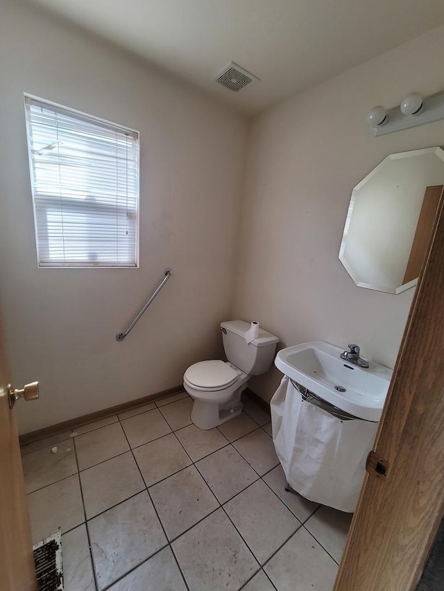 bathroom with visible vents, baseboards, toilet, a sink, and tile patterned flooring