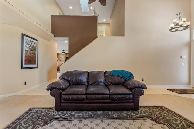 carpeted living area featuring ceiling fan with notable chandelier, recessed lighting, a high ceiling, tile patterned floors, and baseboards