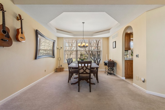dining room featuring visible vents, arched walkways, a wealth of natural light, a chandelier, and a tray ceiling