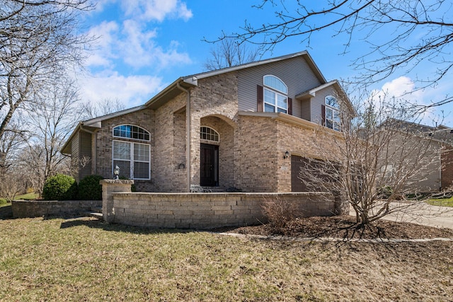 view of front of property featuring a front yard, brick siding, driveway, and an attached garage