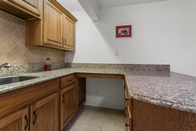 kitchen featuring light countertops, brown cabinets, decorative backsplash, and a sink