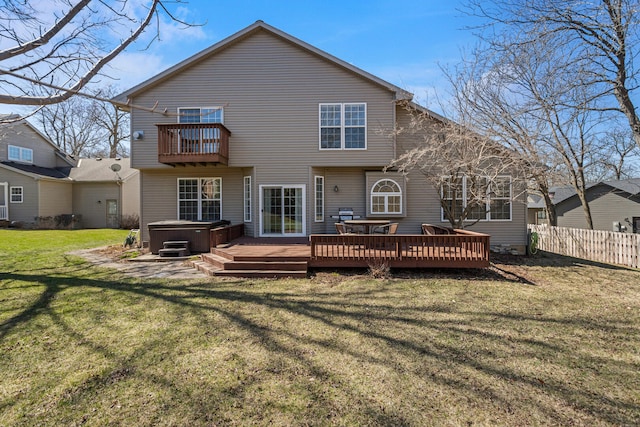 back of property with a yard, a balcony, fence, and a hot tub