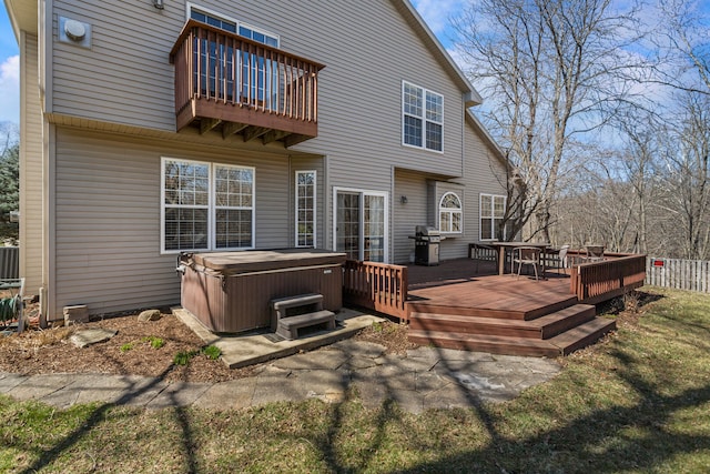 back of house with fence, a deck, a balcony, and a hot tub