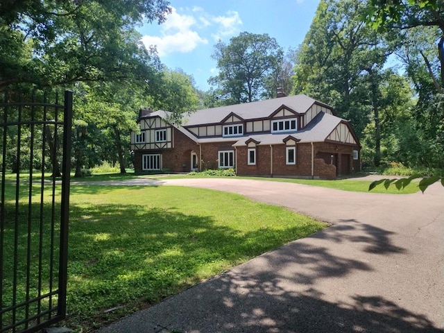 4 Auburn Ln, Barrington Hills, IL 60010 - tudor house featuring curved driveway, a front lawn, brick siding, and a chimney
