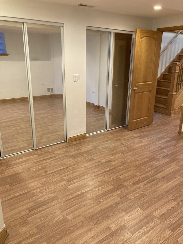 unfurnished bedroom featuring visible vents, multiple closets, and light wood-type flooring