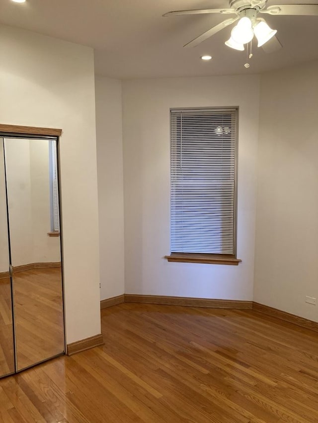 unfurnished bedroom featuring a closet, ceiling fan, baseboards, and wood finished floors