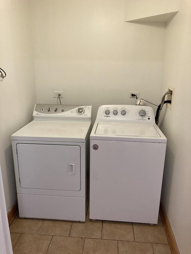 washroom featuring light tile patterned flooring, laundry area, washing machine and dryer, and baseboards