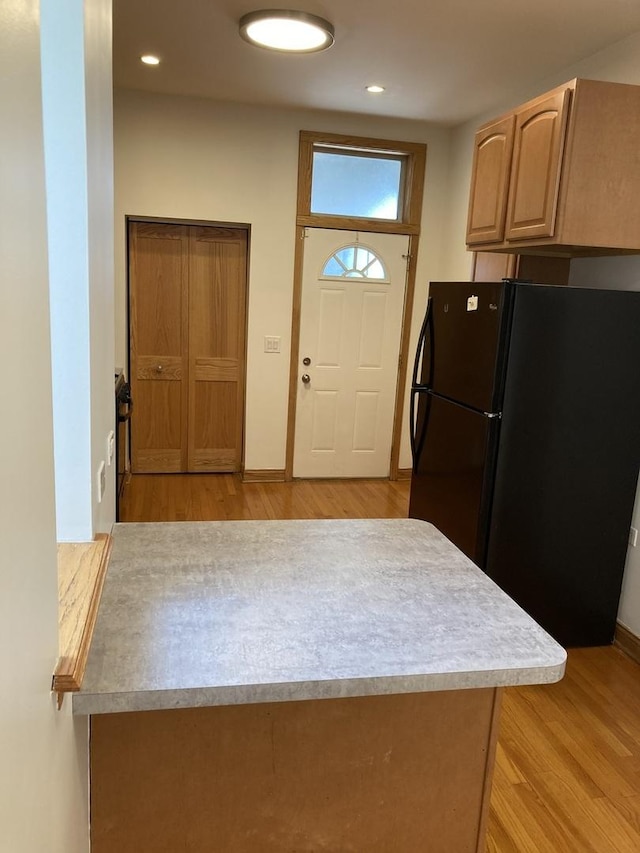 kitchen with freestanding refrigerator, recessed lighting, light wood finished floors, baseboards, and light countertops