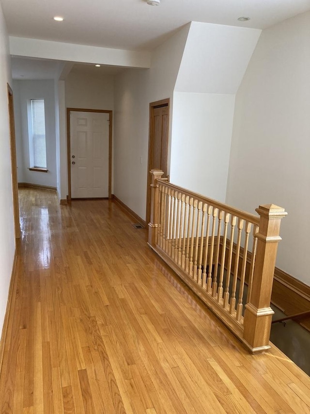 hall featuring an upstairs landing, baseboards, and light wood finished floors