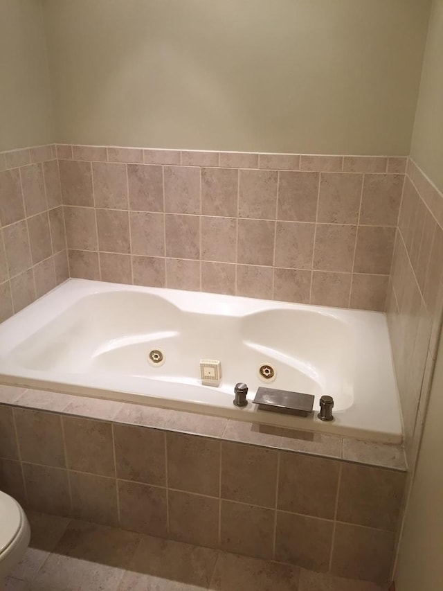 full bath with tile patterned floors, toilet, and a whirlpool tub