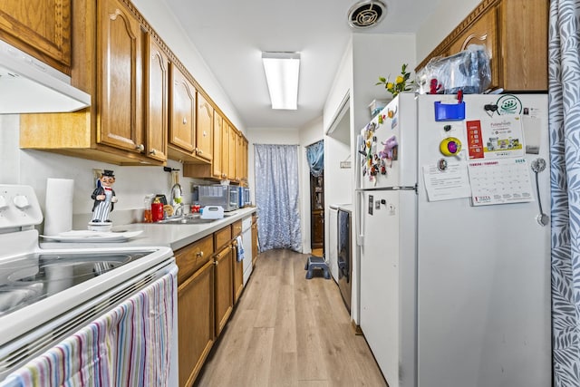 kitchen featuring white appliances, visible vents, light wood-style flooring, under cabinet range hood, and brown cabinets