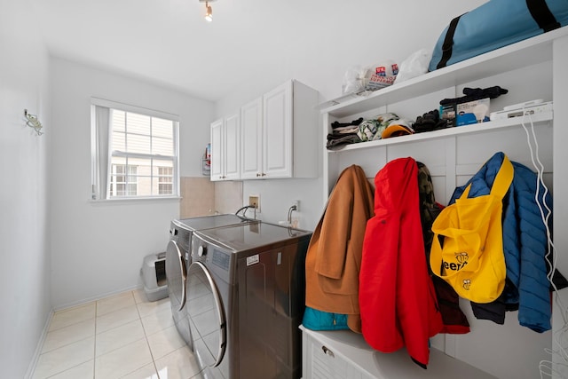 laundry area featuring light tile patterned floors, washer and dryer, cabinet space, and baseboards