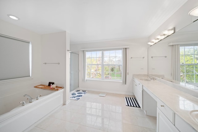 bathroom with a sink, double vanity, a stall shower, baseboards, and a garden tub