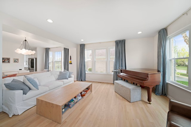 living area with baseboards, recessed lighting, light wood-style flooring, and plenty of natural light