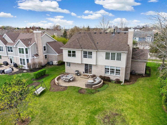 rear view of property with a patio area, a yard, a chimney, brick siding, and entry steps