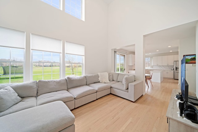 living room with light wood-style floors, recessed lighting, and a high ceiling