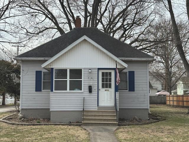 bungalow-style house featuring entry steps, a shingled roof, a chimney, and fence