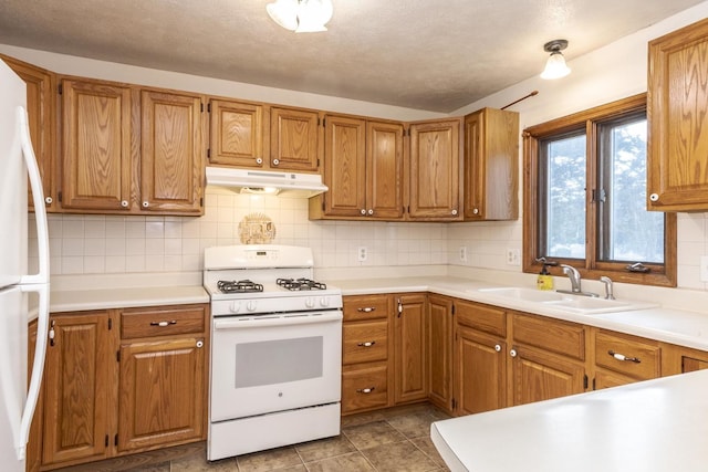kitchen with tasteful backsplash, a sink, white appliances, light countertops, and under cabinet range hood