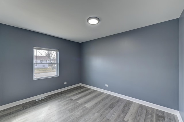 unfurnished room featuring wood finished floors, baseboards, and visible vents