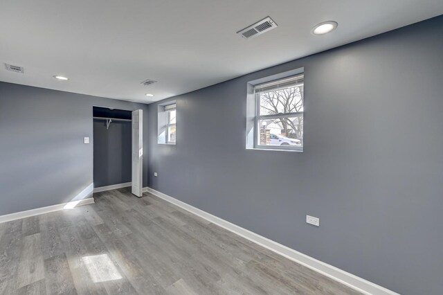 unfurnished bedroom featuring wood finished floors, baseboards, and visible vents