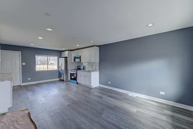 unfurnished living room with dark wood finished floors, recessed lighting, baseboards, and a sink