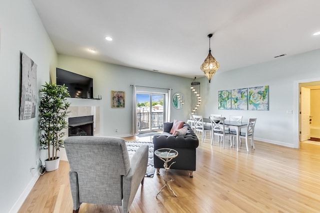 living room with baseboards, a fireplace, light wood-style floors, and recessed lighting