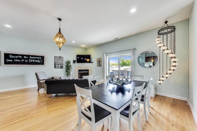 dining room with a tiled fireplace, baseboards, light wood-style floors, and recessed lighting