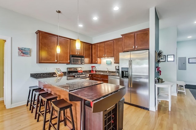 kitchen featuring a sink, appliances with stainless steel finishes, a peninsula, and light wood finished floors