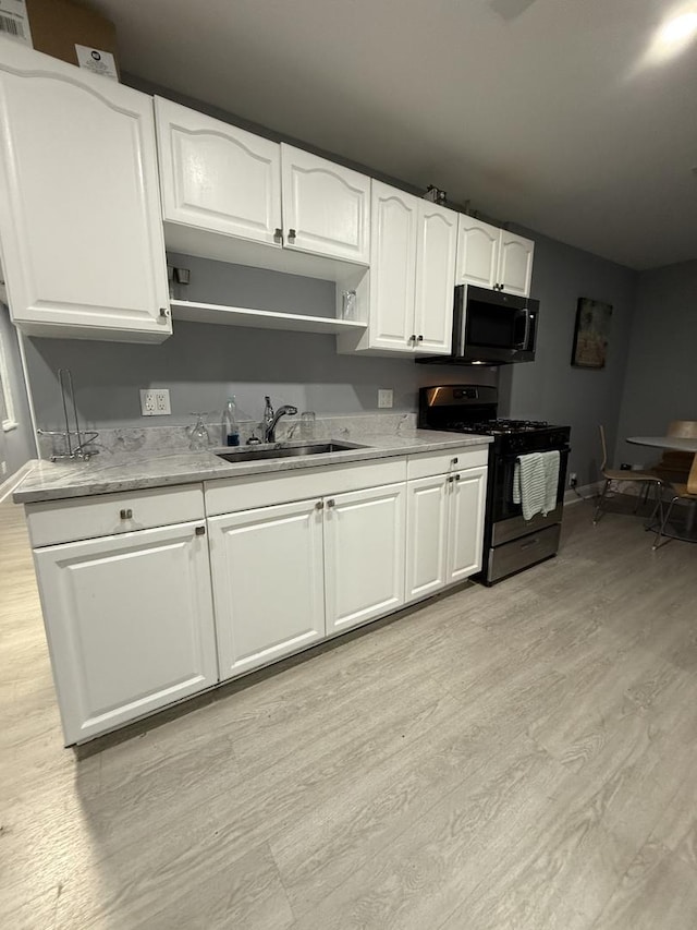 1812 W Erie St, Chicago, IL 60622 - kitchen with white cabinets, range with gas stovetop, a sink, and light wood-style flooring