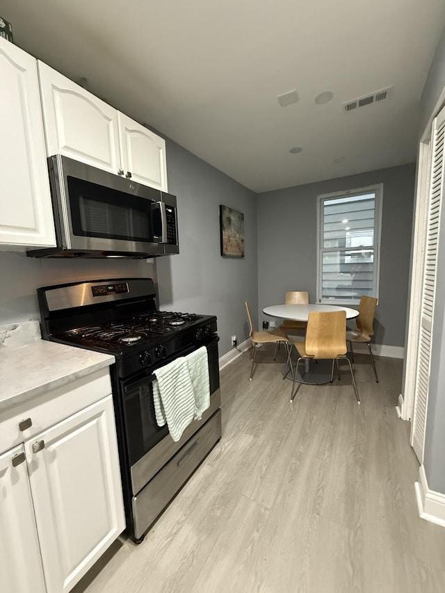 1812 W Erie St, Chicago, IL 60622 - kitchen with stainless steel microwave, light countertops, white cabinets, gas range, and visible vents