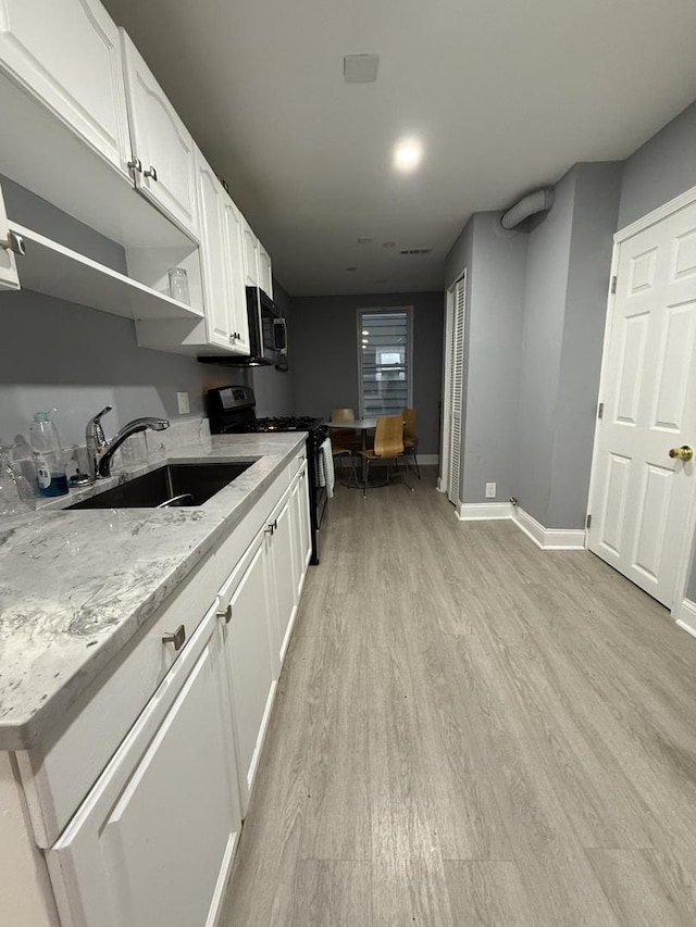 1812 W Erie St, Chicago, IL 60622 - kitchen with stainless steel gas stove, light wood-style floors, open shelves, white cabinets, and a sink