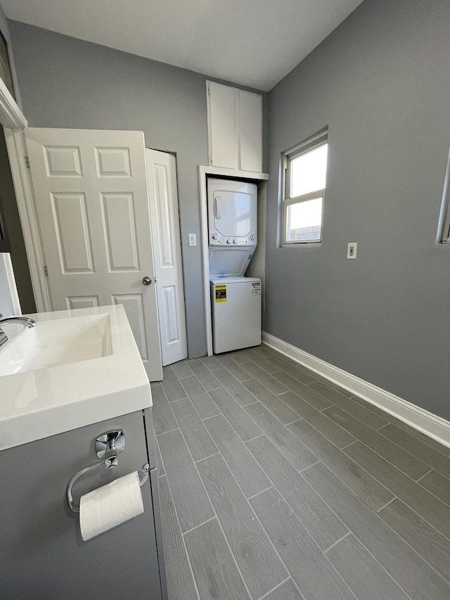 1812 W Erie St, Chicago, IL 60622 - laundry room with baseboards, stacked washing maching and dryer, laundry area, a sink, and wood finished floors