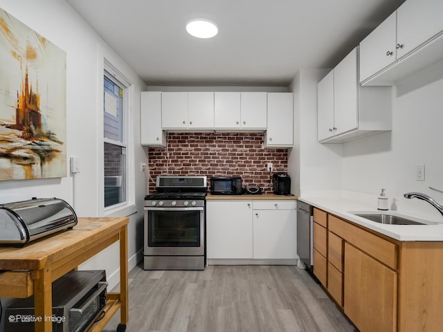 1812 W Erie St, Chicago, IL 60622 - kitchen featuring a sink, light countertops, appliances with stainless steel finishes, white cabinetry, and light wood-style flooring