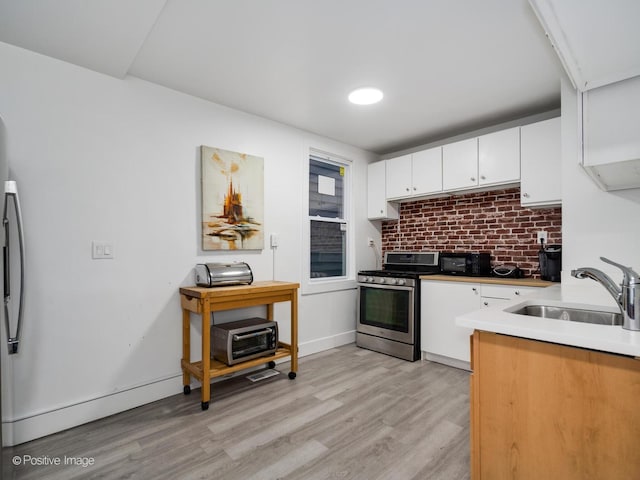 1812 W Erie St, Chicago, IL 60622 - kitchen featuring tasteful backsplash, white cabinets, a sink, gas stove, and light wood-style flooring