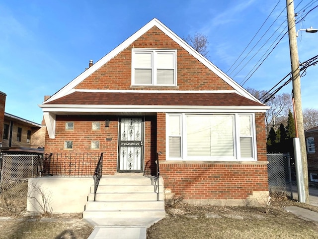 bungalow featuring a porch, fence, and brick siding