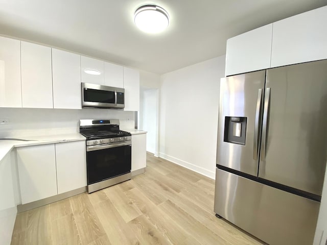 kitchen with modern cabinets, light wood-type flooring, appliances with stainless steel finishes, and light countertops