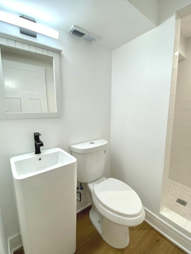 bathroom featuring visible vents, toilet, wood finished floors, a shower stall, and baseboards