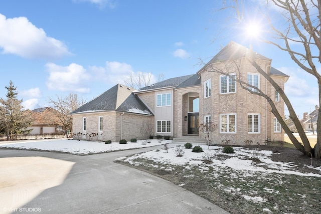 traditional-style home featuring brick siding and roof with shingles