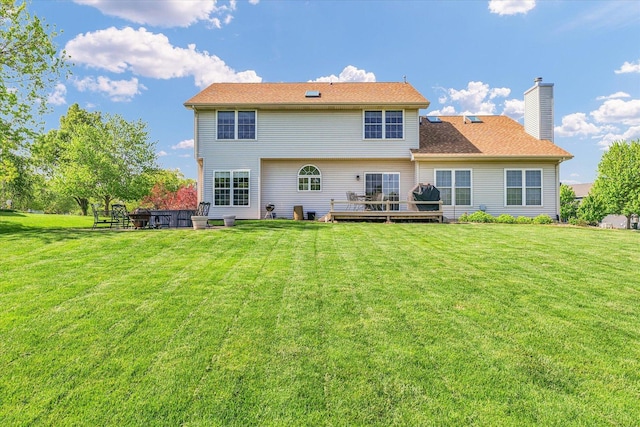 1310 Kimela Dr, Mahomet, IL 61853 - rear view of house featuring a chimney, a lawn, and a wooden deck