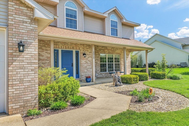 1310 Kimela Dr, Mahomet, IL 61853 - doorway to property featuring brick siding, a porch, and roof with shingles